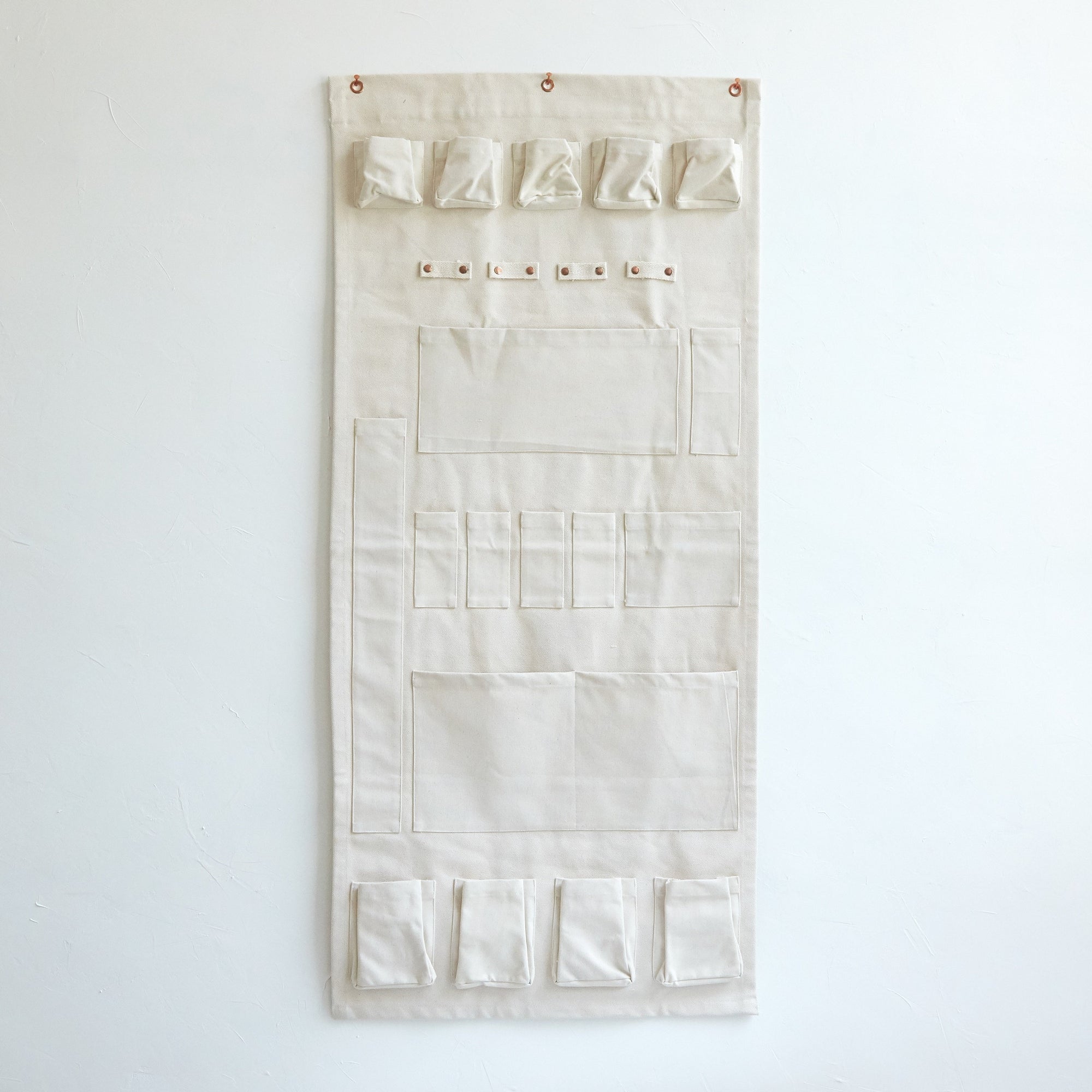 Our wall organizer features 23 durable compartments in a variety of sizes to accommodate a multitude of supplies. Made of heavy-gauge cotton canvas with copper rivets, this versatile design will look great while tidying your workshop, kitchen, closet, or playroom.
